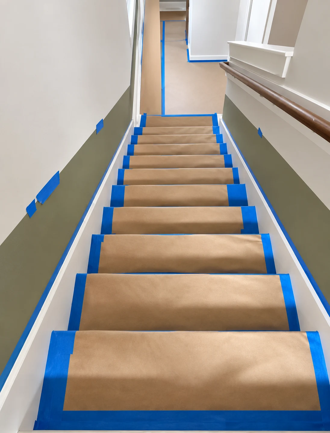 Stair treads covered with brown paper secured with blue painter tape