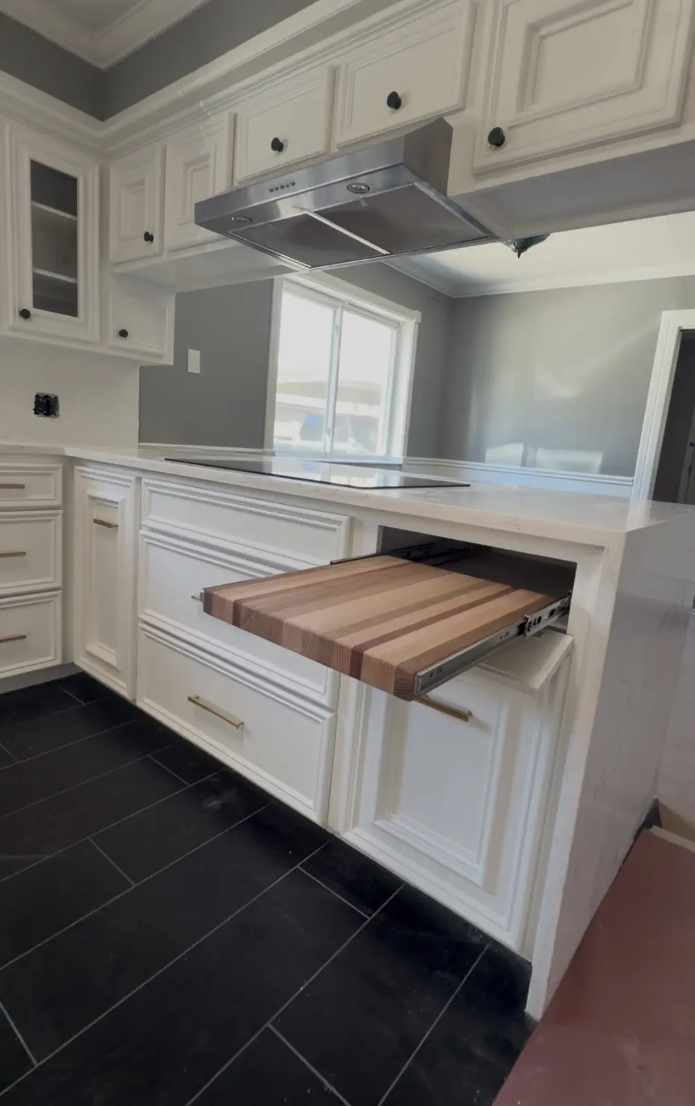 White kitchen cabinetry with wood island countertop and dark flooring